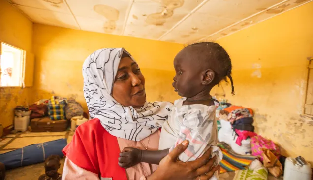Wajdan Hassan Ahmed, SRCS volunteer, holds a young child in her arms