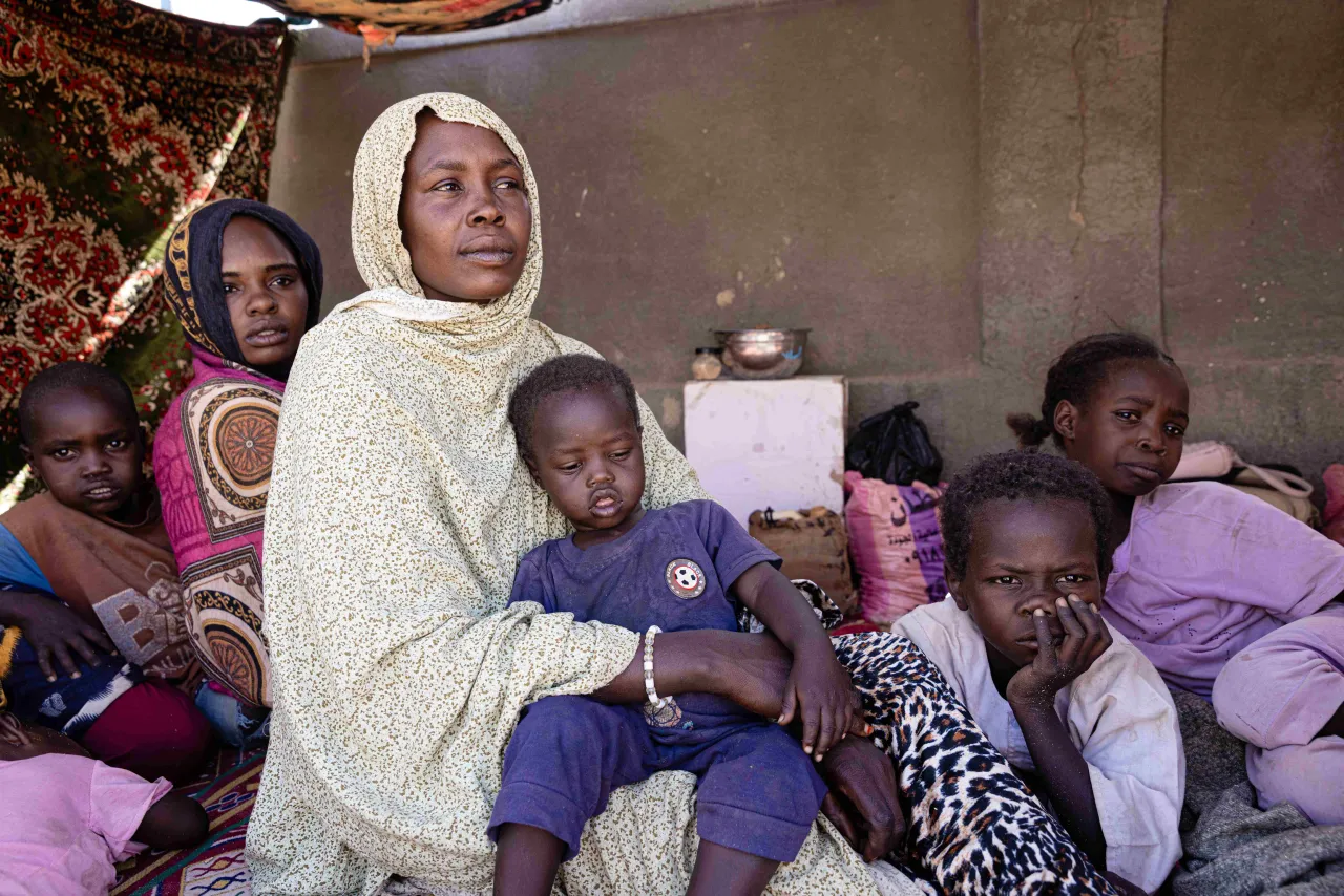 Khadija Adam Youssouf, Sudanese refugee in Tiné sits in a tent with a child on her lap and her other children surrounding her Khadija Adam Youssouf, Sudanese refugee in Tiné sits in a tent with a child on her lap and her other children surrounding her